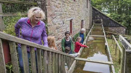 Family exploring the working watermill at Acorn Bank, Cumbria